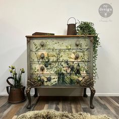 an old dresser with flowers painted on it and some plants growing out of the drawers