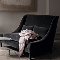 a living room with a black chair and a white table in front of a painting