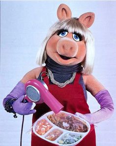 the miss piggy is holding a bowl of food and an electric hair dryer