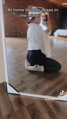 a woman sitting on the floor taking a selfie with her cell phone in front of her