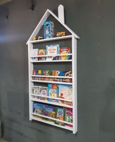 a white book shelf with books on it against a gray wall in a child's room