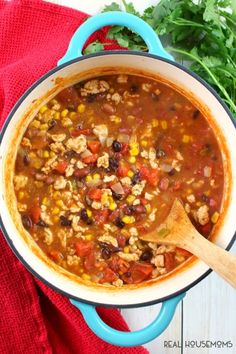 a large pot filled with chili and corn next to cilantro on top of a red towel