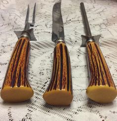 three knives and two forks sitting on top of a table