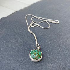 "Coming Down, Coming Down" Excellent multi-shades of green, a pretty spiderweb Hubei Turquoise round cabochon is set in fine and sterling silver, tumbled for a bright finish. Pendant measures approximately 20mm (including bail) by 15.5mm. 18" sterling silver bead chain with a sterling lobster clasp. Artisan Chrysocolla Necklace, Green Turquoise Necklace With Large Sterling Silver Pendant, Unique Turquoise Necklace With Natural Stones, Green Cabochon Round Necklaces, Unique Round Turquoise Necklace With Natural Stones, Green Turquoise Pendant Necklace In Sterling Silver, Green Sterling Silver Turquoise Pendant Necklace, Handmade Turquoise Sterling Silver Round Pendant Necklace, Green Turquoise Gemstone Necklace In Sterling Silver