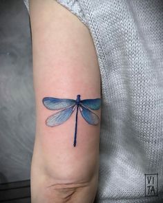 a blue dragonfly tattoo on the arm