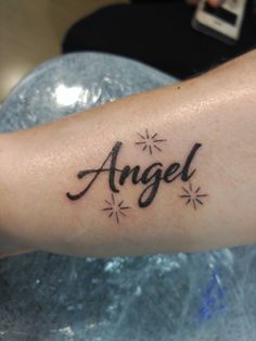 an arm with the word angel written on it and stars around it in black ink