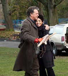 a man and woman standing next to each other in the grass