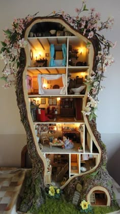 a doll house built into the side of a tree trunk with flowers growing out of it