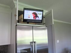 a television on top of a refrigerator in a kitchen