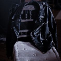 a black leather jacket sitting on top of a white chair