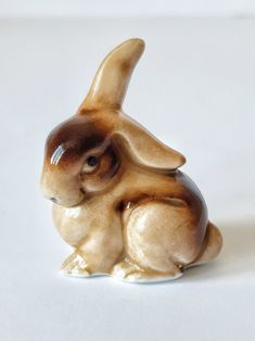 a ceramic figurine of a rabbit on a white surface with one eye open