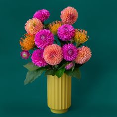 A beautiful chartreuse fluted cylindrical vase sits in middle of a page.  Inside the vase are beautiful Dahlia flowers- orange, pink and coral.  There are green leaves spilling out of the vase.  The flowers and vase are on a beautiful aquamarine colored background. Fun Flower Arrangements, Colorful Flower Pots, Funky Flower Vase, Retro Vase, Statement Vase, Unique Vase, Dried Florals, Whimsical Home, Therapy Office