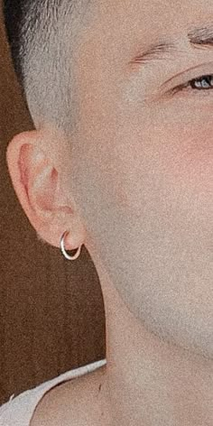 a close up of a person with an earring on their head and wearing a white shirt