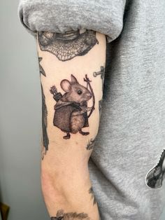 a person with a tattoo on their arm holding a mouse and an arrow in his hand