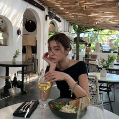 a woman sitting at a table with a glass of wine and food in front of her