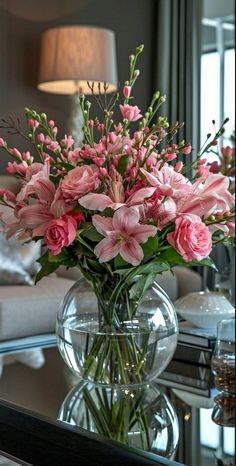 a vase filled with pink flowers sitting on top of a table next to a couch