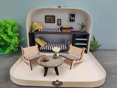 a miniature living room with two chairs and a table in the shape of an open suitcase