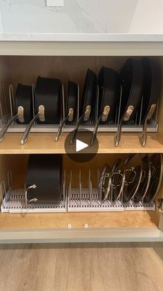 a kitchen cabinet filled with lots of black pots and pans