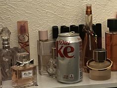 several different types of perfumes and bottles on a shelf with white wall behind them