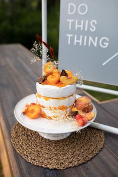 a three tiered cake sitting on top of a wooden table next to a do this thing sign