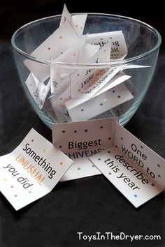 a glass bowl filled with lots of small cards next to each other on top of a table