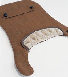 a brown piece of cloth with buttons on the front and back of it, sitting on top of a white surface