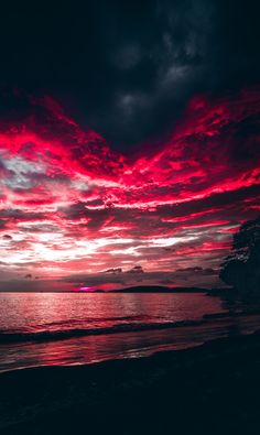 the sun is setting over the ocean with red clouds in the sky and dark water