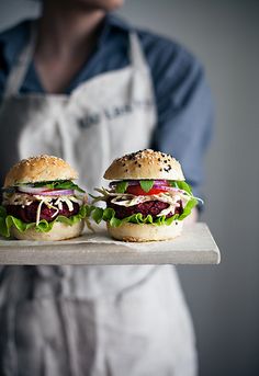 two hamburgers with lettuce and tomato on a tray