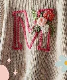 a knitted sweater with flowers and the letter m on it's chest is shown