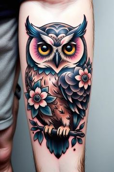 an owl tattoo on the leg with flowers and leaves around its neck, in front of a man's arm