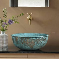 a blue bowl sitting on top of a counter next to a vase