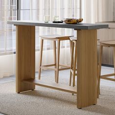 a kitchen island with two stools in front of it and a bowl on the counter