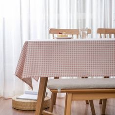 a table with a checkered cloth on it in front of a white curtained window