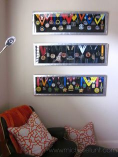 three medals are hung on the wall above a couch with two pillows and a lamp