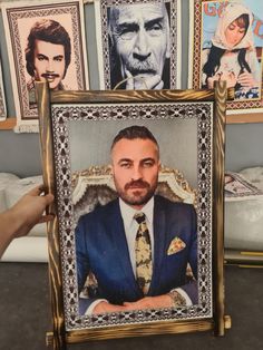 a man in a suit and tie holding up a framed photo