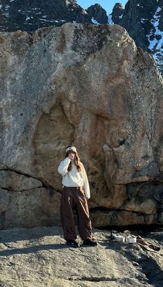 a woman standing in front of a large rock