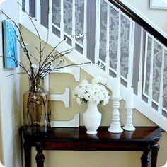 a table with vases and flowers on it in front of the bannister