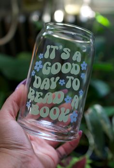 a hand holding a glass with the words it's a good day to read a book