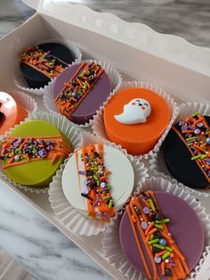 cupcakes decorated with sprinkles and icing in a white box