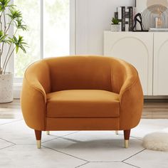 an orange chair sitting on top of a white rug next to a potted plant