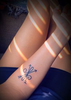 a woman's legs with a tattoo on her left arm and an arrow in the middle