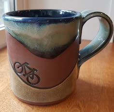 a coffee cup with a bicycle on it sitting on a table next to a window