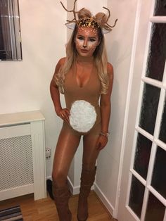 a woman dressed as a deer with horns on her head is standing in front of a door