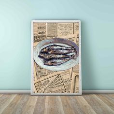 an image of fish in a bowl on top of newspaper paper with blue wall and wooden floor