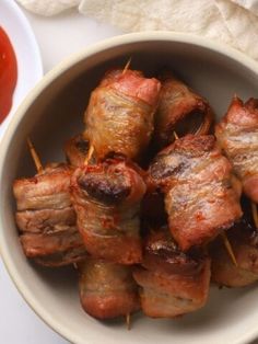 bacon wrapped chicken skewers in a bowl with ketchup