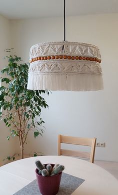 a potted plant sitting on top of a table under a hanging light over a dining room table