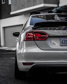 the back end of a silver car parked in front of a building