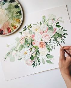 a person is painting flowers on a piece of paper with watercolors and paintbrushes