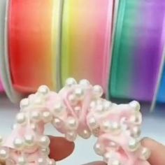 a person is holding some pearls in their hand and they are all different colored ribbons