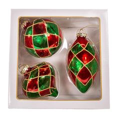 three christmas ornaments in a white box with gold trimmings and red and green designs